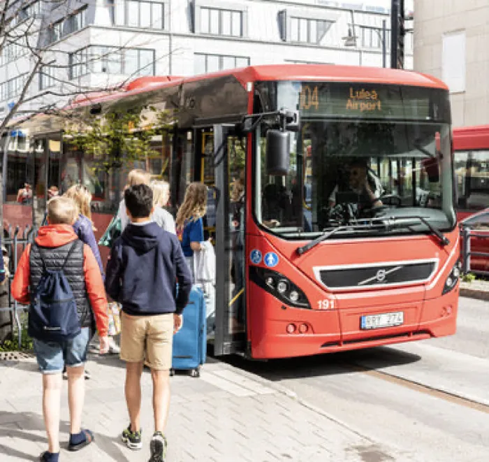 Ungdomar med väskor stiger på en stadsbuss med destinationsskylten Luleå Airport.